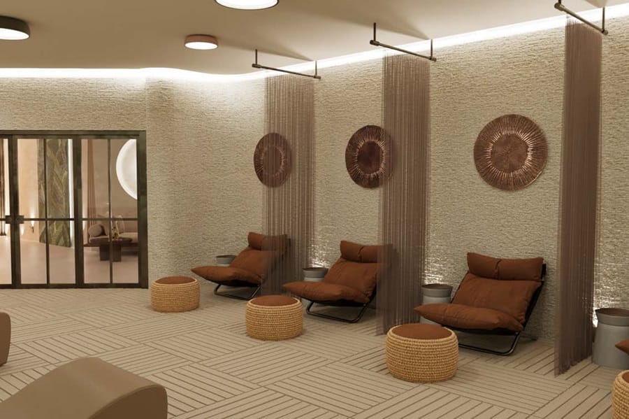 Spa lounge with three brown cushioned lounge chairs along a textured wall, woven stools, and sheer curtains outside seating area.